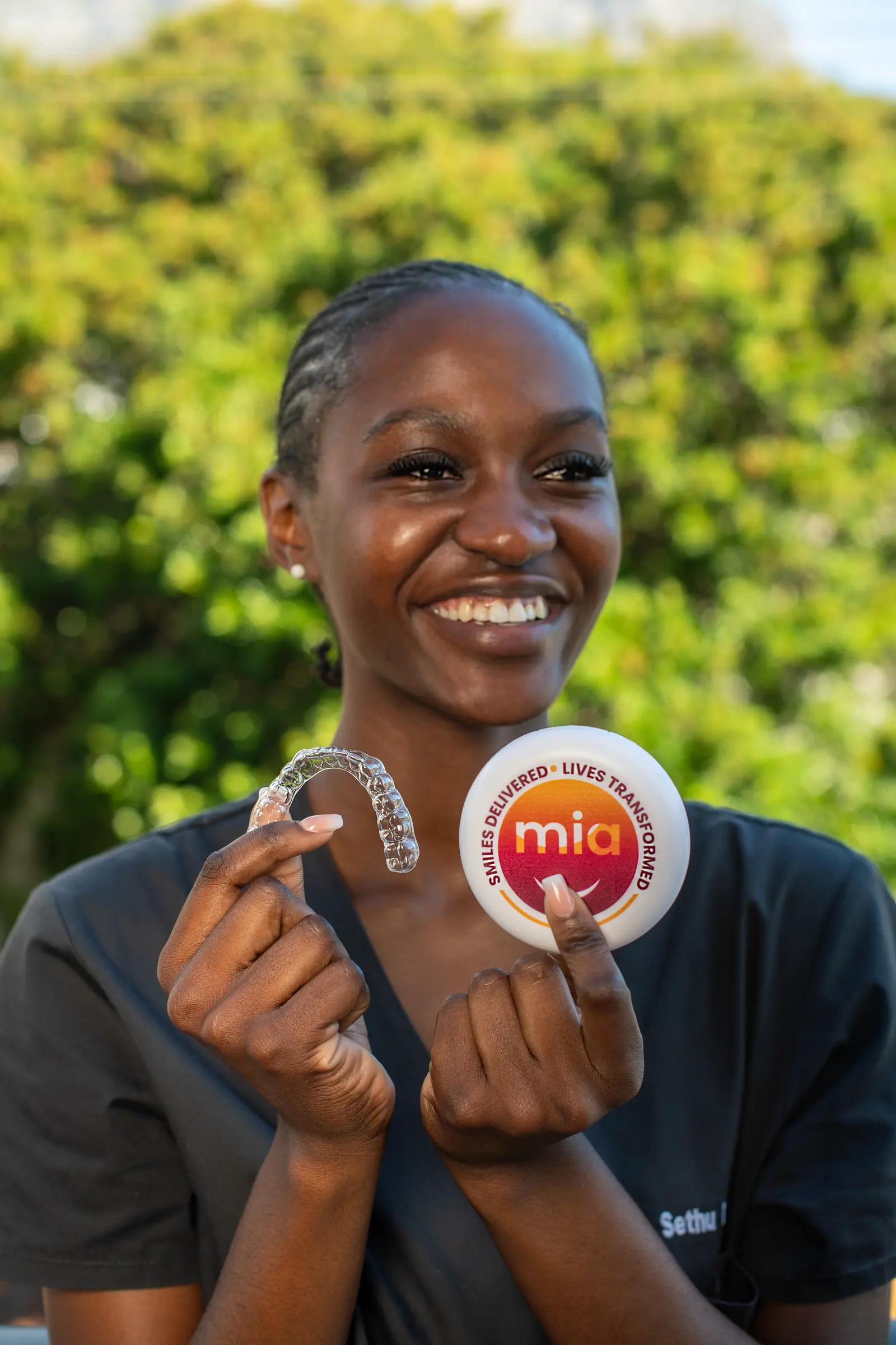 Smiling young woman holding an aligner and case