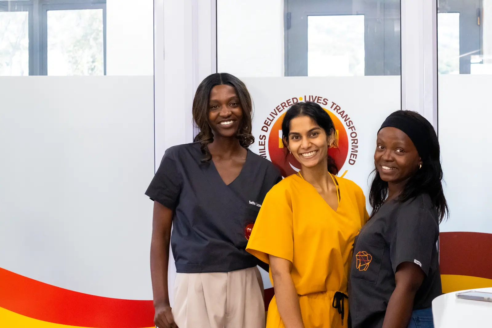 Three Mia Cape Town clinicians in front of the Mia logo